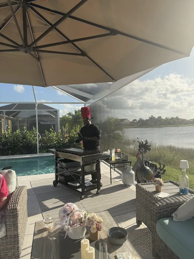 Chef cooking on a grill in a screened lanai overlooking a lake