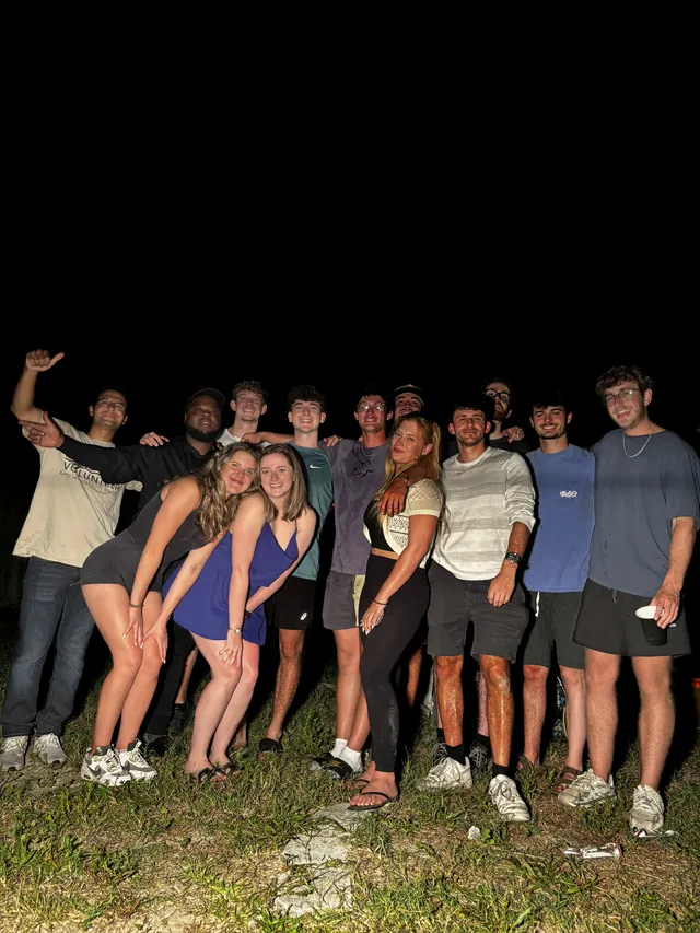 A large group of guests posing together on a lawn at night