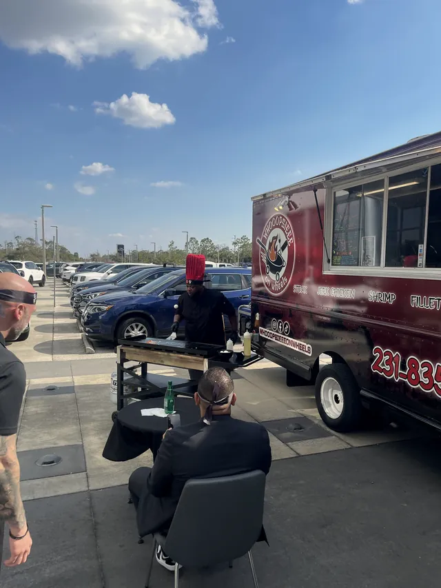 Guests seated at small black tables beside the Whooopsieee food truck